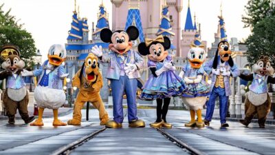 Mickey, Minnie, Pato Donald, Margarida, Pluto, Pateta, Tico e Teco com roupas azuis e lilás em frente ao castelo da Cinderela, no Magic Kingdom